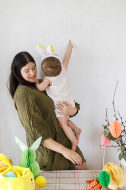 Mutlu Paskalyalar! Sevimli bebek tavşancık ve mutlu anne renkli paskalya kâğıdı yumurtaları, şenlikli dekorasyon ve havuçlarla sarılıp oynuyorlar. Sevimli Paskalya tavşanı ve Paskalya avı.