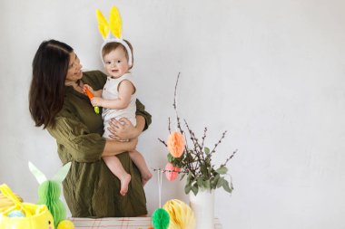 Mutlu Paskalyalar! Sevimli bebek tavşancık ve mutlu anne renkli paskalya kâğıdı yumurtaları, şenlikli dekorasyon ve havuçlarla sarılıp oynuyorlar. Sevimli Paskalya tavşanı ve Paskalya avı.