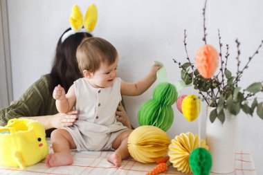 Mutlu Paskalyalar! Sevimli bebek tavşancık ve mutlu anne renkli paskalya kâğıdı yumurtaları, şenlikli dekorasyon ve havuçlarla birlikte oynuyorlar. Sevimli Paskalya tavşanı ve Paskalya avı.