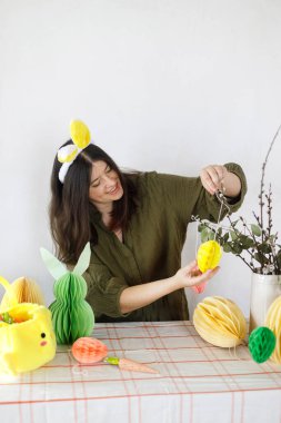 Tavşan kulaklı mutlu kadın renkli paskalya kâğıdı yumurtaları, vazo ve havuçlarla süslüyor. Mutlu Paskalyalar! Paskalya sofrası kurma ve Paskalya avı.