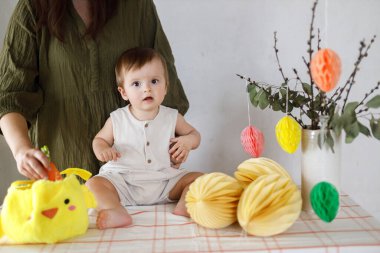 Mutlu Paskalyalar! Sevimli bebek ve mutlu anne renkli paskalya kâğıdı yumurtaları, şenlikli dekorasyon ve havuçlarla birlikte oynuyorlar. Sevimli Paskalya tavşanı ve Paskalya avı.