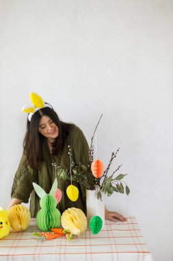 Mutlu Paskalyalar! Tavşan kulaklı şık bir kadın renkli paskalya yumurtaları, tavşanlar ve havuçlarla süslüyor. Paskalya sofrası kurma ve Paskalya avı.