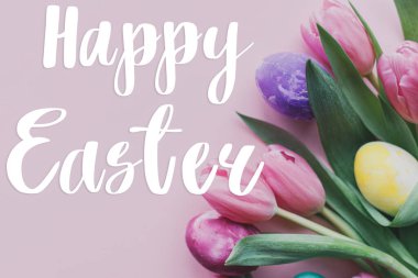 Mutlu Paskalyalar! Paskalya mesajlı tebrik kartı, Paskalya yumurtası ve lale çiçekli pembe arka planda yatıyordu.