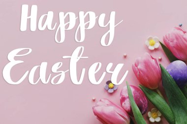 Mutlu Paskalyalar! Paskalya mesajlı tebrik kartı, Paskalya yumurtası ve lale çiçekli pembe arka planda yatıyordu.