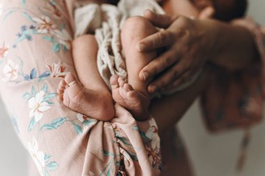 Anneler Günün kutlu olsun! Yeni doğmuş küçük ayaklar annesinin ellerinde. Annesi kucak dolusu tatlı bir bebek. Annelik ve ebeveynlik. Evlat edinme ve doğurganlık kavramı