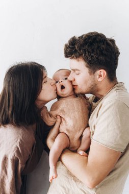 Mutlu anne ve baba öpüşüyor ve küçük oğluna sarılıyor. Anneler günün kutlu olsun ve babalar günün kutlu olsun! Annelik ve ebeveynlik. Evlat edinme ve doğurganlık kavramı