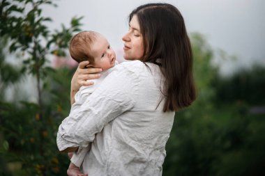 Anne bahçede sevimli yeni doğmuş bebeği öpüyor ve sarılıyor. Yaklaş. Kırsal alanda sevgi, ilgi ve aile. Anneler Günün kutlu olsun! Evlat edinme ve annelik