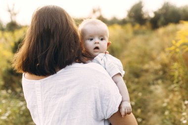 Mutlu anne, yeni doğmuş bebeği akşamları çayırda tutuyor. Aşk ve aile kavramı. Anne ve tatlı oğlu tarlada yürüyor. Anneler günün kutlu olsun.!