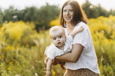 Mutlu anne akşamları çayırda küçük bebekle oynuyor. Aşk, ilgi ve aile kavramı. Anne ve tatlı oğlu sahada eğleniyor. Anneler günün kutlu olsun.!