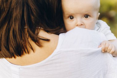 Annesinin elinde küçük şirin bir bebeğin portresi. Anne, yeni doğmuş bebeğe akşamları çayırda sarılıyor. Aşk, ilgi ve koruma konsepti. Anne ve oğlu. Anneler günün kutlu olsun.!