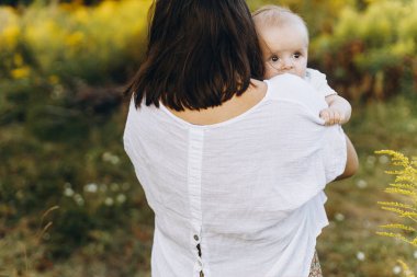 Anne, yaz otlağında yeni doğmuş bebeğe sarılıyor, annesinin elinde küçük şirin bir bebeğin portresi. Aşk, ilgi ve koruma konsepti. Anne ve oğlu. Anneler günün kutlu olsun.!
