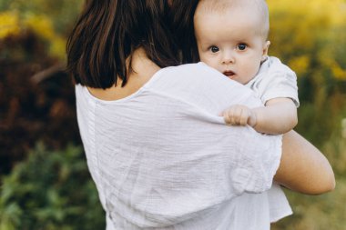 Anne, yaz otlağında yeni doğmuş bebeğe sarılıyor, annesinin elinde küçük şirin bir bebeğin portresi. Aşk, ilgi ve koruma konsepti. Anne ve oğlu. Anneler günün kutlu olsun.!