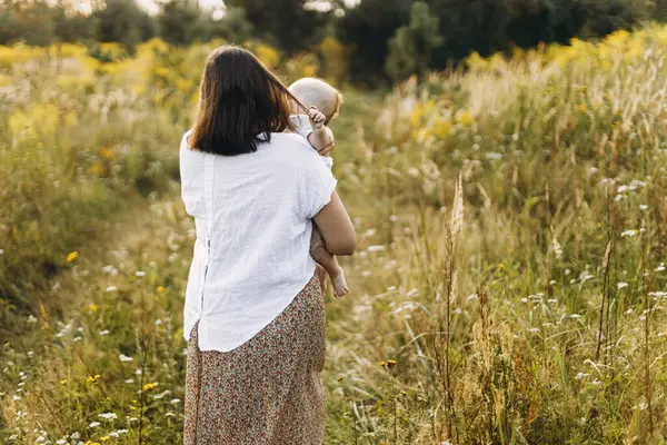 Mutlu anne, yeni doğmuş bebeği akşamları çayırda tutuyor. Aşk ve aile kavramı. Anne ve tatlı oğlu tarlada yürüyor. Anneler günün kutlu olsun.!