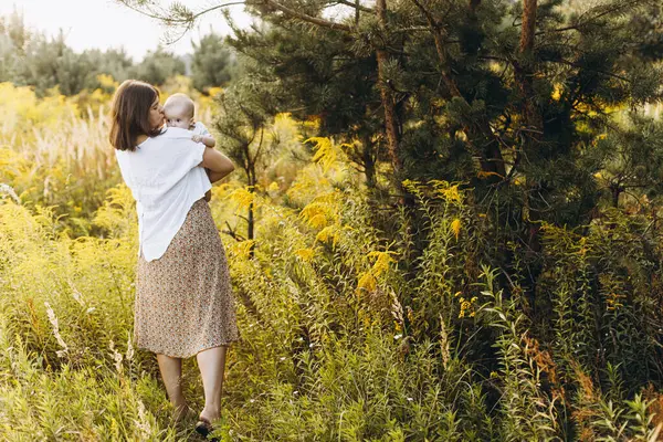 Mutlu anne, yeni doğmuş bebeği akşamları çayırda tutuyor. Aşk ve aile kavramı. Anne ve tatlı oğlu tarlada yürüyor. Anneler günün kutlu olsun.!