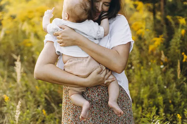 Mutlu anne, yeni doğmuş bebeğini akşam çayırda kucaklıyor. Aşk, ilgi ve aile kavramı. Anne ve tatlı oğlu tarlada yürüyor. Anneler günün kutlu olsun.!