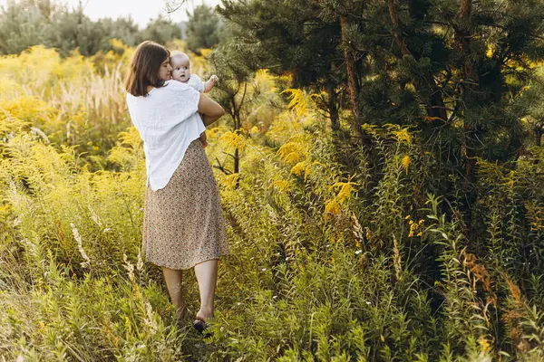 Mutlu anne, yeni doğmuş bebeği akşamları çayırda tutuyor. Aşk ve aile kavramı. Anne ve tatlı oğlu tarlada yürüyor. Anneler günün kutlu olsun.!