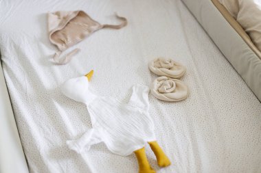 Modern bebek karyolasında şık bebek kıyafetleri, oyuncak, yorgan, yakın çekim. Hamilelik ve bebek için hazırlanmak. Hazırlık ve çocuk odası