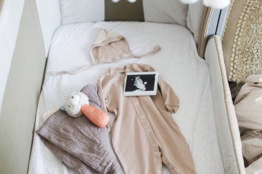 Hamilelik ve bebek için hazırlanmak. Modern bebek beşiği şık bebek kıyafetleri, oyuncak, cep telefonu, ultrason resmi. Hazırlık ve çocuk odası hazırlığı.