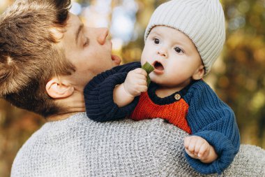 Sonbahar ormanlarında yaprakları elinde tutan sevimli bir oğlan çocuğu babasının ellerinde. Babalık. Hoş çocuklu şık bir adam rahat kazaklar içinde sonbahar parkında dinleniyor.