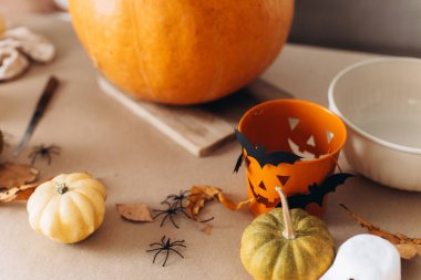 Mutlu Cadılar Bayramı. Cadılar bayramı için masaya balkabağı oyma, Cadılar Bayramı süsü, şaka mı şeker mi kovası, örümcekler ve yarasalar yaklaşır. Aile Jack O Feneri yapıyor, Tatil hazırlığı detayları