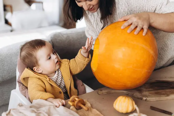 Mutlu anne ve tatlı oğlu masalara hayaletler, örümcekler ve yarasalarla balkabağı oyuyor. Cadılar bayramı balkabağı kesimi, balkabağı feneri yapmak. Cadılar Bayramı hazırlığı