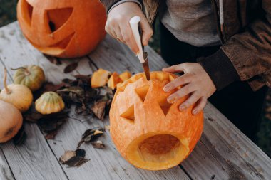 Kriko feneri yapıyorum. Sonbahar bahçesindeki ahşap masaya cadılar bayramı balkabağı oyan eller, eller kapalı. Sonbahar hasadı. Balkabağı kesiyorum. Cadılar Bayramı hazırlığı