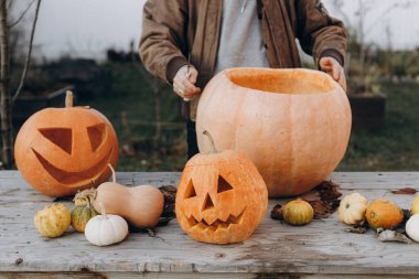Kriko feneri yapıyorum. Sonbahar bahçesindeki ahşap masaya cadılar bayramı balkabağı oyan eller, eller kapalı. Sonbahar hasadı. Balkabağı kesiyorum. Cadılar Bayramı hazırlığı