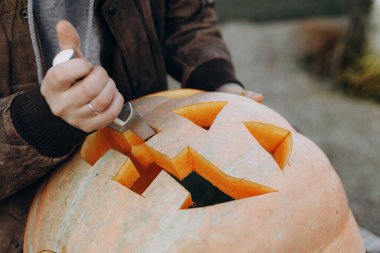 Kriko feneri yapıyorum. Sonbahar bahçesindeki ahşap masaya cadılar bayramı balkabağı oyan eller, eller kapalı. Sonbahar hasadı. Balkabağı kesiyorum. Cadılar Bayramı hazırlığı
