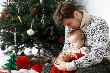 Mutlu bir baba ve şirin bir oğul Noel ağacının arka planında ışıkları olan şık bir hediye kutusu tutuyorlar. Mutlu Noeller ve mutlu tatiller! Atmosferik aile zamanı.