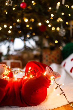 Mutlu Noeller ve mutlu tatiller! Altın çelenk içindeki şirin bebek ayakları süs ve hediyelerle noel ağacının altında. Sevimli Bebek ilk Noel kutlaması konsepti