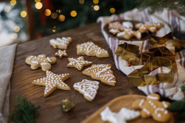 Kırsal masada Noel kurabiyeleri, metal kesiciler, peçeteler, Noel ağacı ışıklarının arka planında köknar dalları. Noel aile gelenekleri, tatil kurabiyeleri