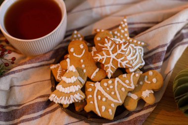 Mutlu Noeller! Zencefilli Noel kurabiyeleri, sıcak bir fincan çay ve masa düzlüğünde duran süsler. Sıcak kış zamanı