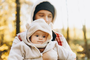 Mutlu baba, sonbahar ormanında yumuşak bir akşam ışığında tatlı oğluna sarılıyor. Babalık. Hoş çocuklu şık bir adam rahat kazaklar içinde sonbahar parkında dinleniyor.