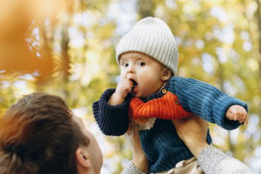 Mutlu baba sonbahar ormanlarında tatlı oğluyla oynuyor. Babalık. Sevimli çocuğu olan şık bir adam sıcak kazaklar içinde sonbahar parkında eğleniyor ve dinleniyor.