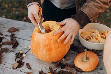 Kriko feneri yapıyorum. Sonbahar bahçesindeki ahşap masaya cadılar bayramı balkabağı oyan eller, eller kapalı. Sonbahar hasadı. Balkabağı kesiyorum. Cadılar Bayramı hazırlığı