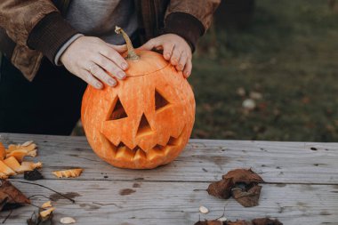 Kriko feneri yapıyorum. Sonbahar bahçesindeki ahşap masaya cadılar bayramı balkabağı oyan eller, eller kapalı. Sonbahar hasadı. Balkabağı kesiyorum. Cadılar Bayramı hazırlığı