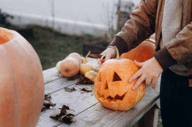 Kriko feneri yapıyorum. Sonbahar bahçesindeki ahşap masaya cadılar bayramı balkabağı oyan eller, eller kapalı. Sonbahar hasadı. Balkabağı kesiyorum. Cadılar Bayramı hazırlığı