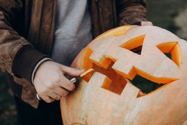 Kriko feneri yapıyorum. Sonbahar bahçesindeki ahşap masaya cadılar bayramı balkabağı oyan eller, eller kapalı. Sonbahar hasadı. Balkabağı kesiyorum. Cadılar Bayramı hazırlığı