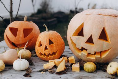 Mutlu Cadılar Bayramı. Balkabağı oyulmuş balkabağı. Sonbahar bahçesindeki ahşap masaya cadılar bayramı balkabağı oymak. Yaklaş. Sonbahar hasadı. Cadılar Bayramı hazırlığı