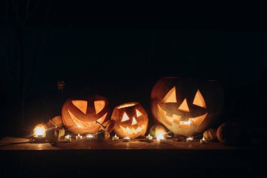 Mutlu Cadılar Bayramı. Karanlık, korkunç bahçedeki kırsal masada mumlarla parlayan balkabağı Jack. Yuh! Şeker mi şaka mı? Ürkütücü atmosferik Cadılar Bayramı gecesi mesaj için boşluk