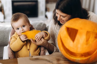 Mutlu anne ve tatlı oğlu masalara hayaletler, örümcekler ve yarasalarla balkabağı oyuyor. Cadılar bayramı balkabağı kesimi, balkabağı feneri yapmak. Cadılar Bayramı hazırlığı