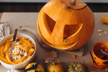 Mutlu Cadılar Bayramı. Cadılar bayramı için masaya balkabağı oyma, Cadılar Bayramı süsü, şaka mı şeker mi kovası, örümcekler ve yarasalar yaklaşır. Aile Jack O Feneri yapıyor, Tatil hazırlığı detayları