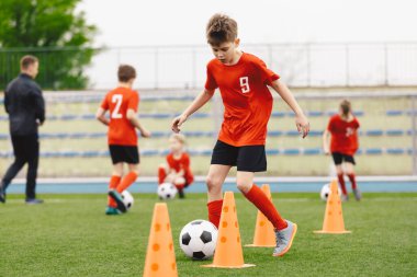 Futbol Antrenmanında Genç Çocuklar. Çocuklar Futbol Toplarıyla Top Sürükleme Antrenmanında Koşuyorlar