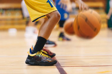 Küçük seviye basketbol oyuncuları sırada basketbol topunu sektiriyorlar. Okul sahasında klasik basketbol oynayan genç basketbolcular. Gençler için basketbol antrenmanı. Okul spor sınıfı