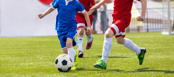 デュエルのサッカー選手 サッカーアカデミーのサッカークラブの小学生 2人の子供スポーツチーム草のピッチでサッカーの試合をキック — ストック写真