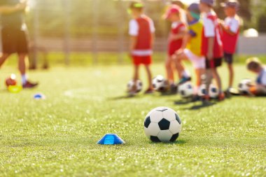 Futbol, antrenman ve çocuklar spor sahasında. Spor sahasında futbol ekipmanları. Futbol topu ve eğitim konisi işaretleyicisi sahada. Spor antrenmanındaki çocuklar