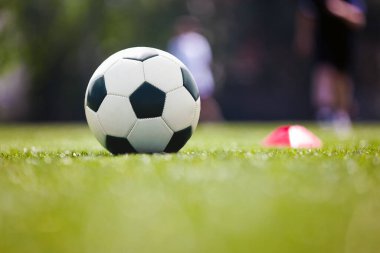 Futbol, antrenman ve çocuklar spor sahasında. Spor sahasında futbol ekipmanları. Futbol topu ve eğitim konisi işaretleyicisi sahada. Spor antrenmanındaki çocuklar