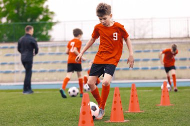 Futbol Eğitiminde Mutlu Çocuk Slalom Tatbikatı. Çimen Okul Sahasında Avrupa Futbolu Çalışan Çocuklar. Futbol Eğitimi - Isınma ve Slalom Tatbikatları