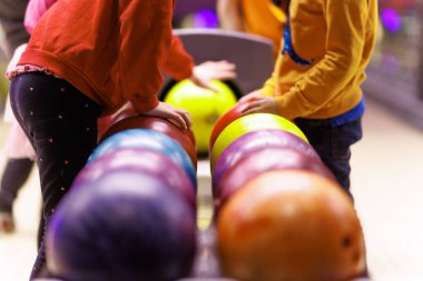 Çocuklar bowling oynuyorlar. Çocuklar için ders dışı aktiviteler. Arka planda bowling topları ve bowling salonu.