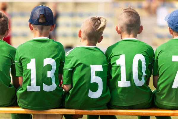 学校的足球运动员坐在木制替补席上 一群男孩子在玩体育比赛游戏 身穿绿色运动服的儿童 — 图库照片